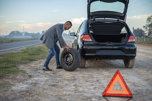 タイヤがパンクして停車してタイヤを交換しようとする人