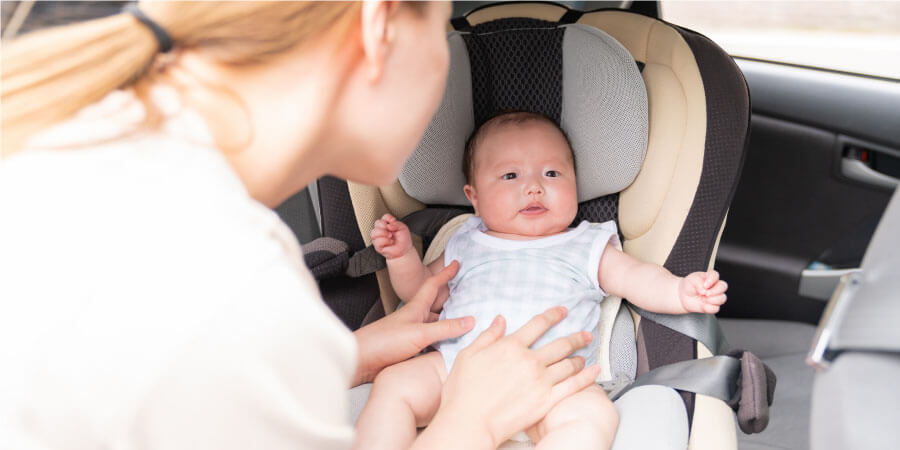 車内の赤ちゃんをお世話する母親　子育てママイメージ