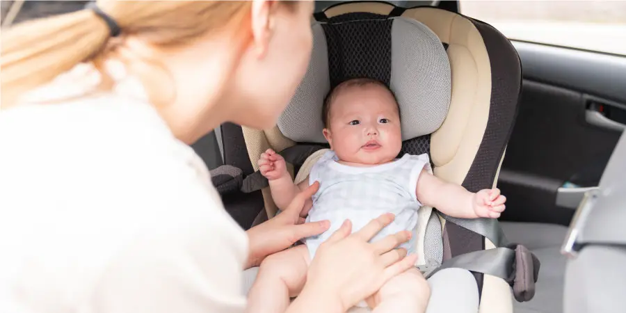 車内の赤ちゃんをお世話する母親 子育てママイメージ