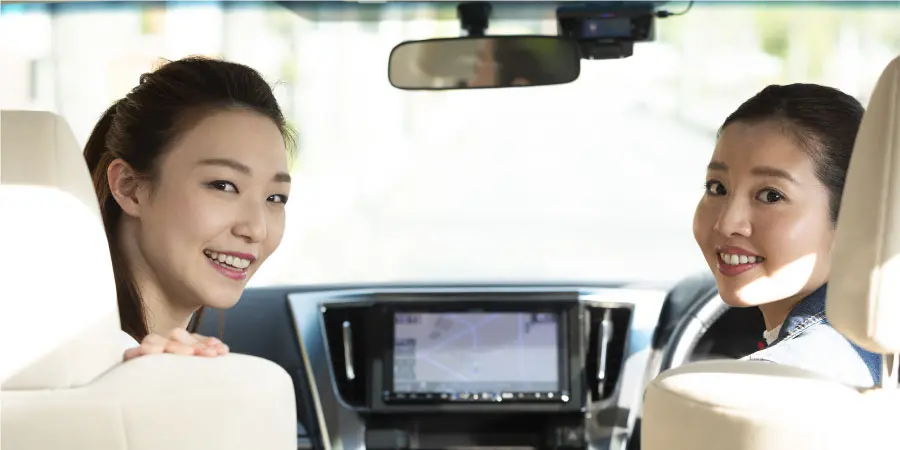 車内で振り向く二人の女性 快適ドライブメージ