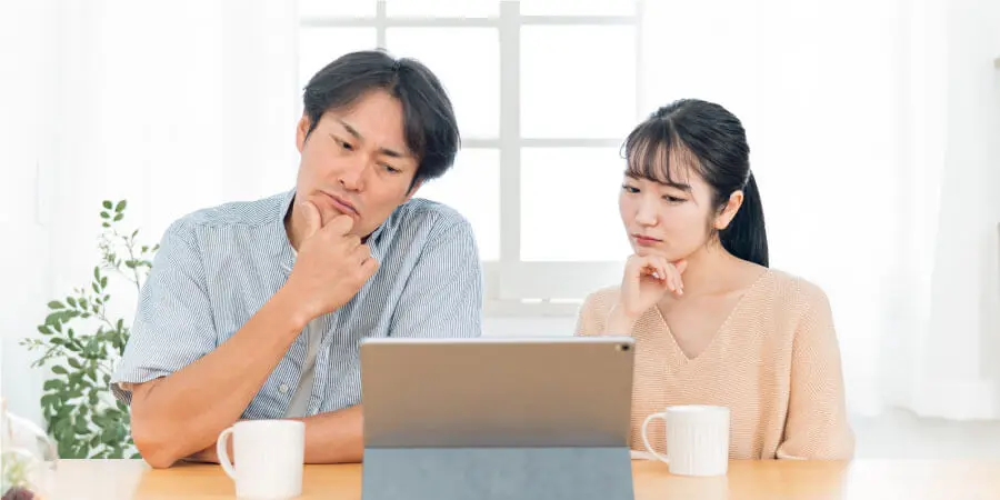 パソコンの画面を見ながら悩む夫婦