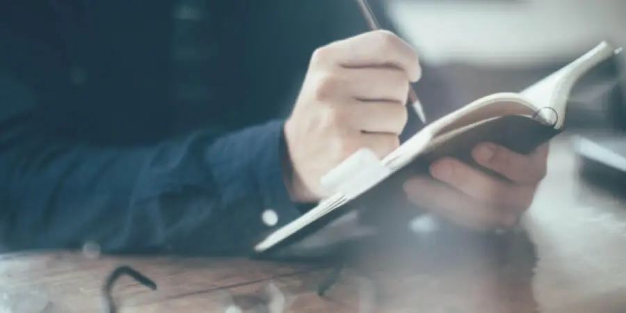 手帳に書き込む男性の手元