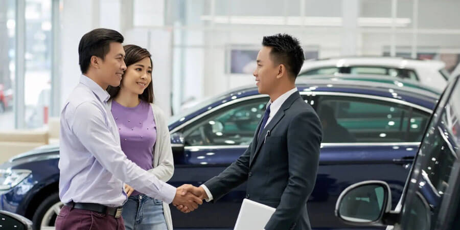 車を購入する夫婦と握手するディーラーの男性