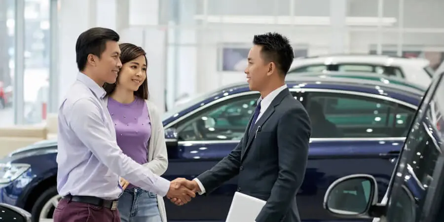 車を購入する夫婦と握手するディーラーの男性