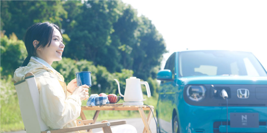 N-ONE e:から電気を取り出して屋外でコーヒーを楽しむ女性